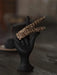 Leopard print hair clips on a black hand-shaped stand with a blurred background