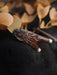 Wooden angel wing figurine on a dark surface with blurred leaves in the background