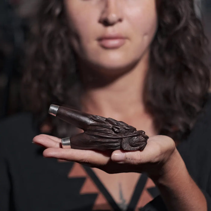 Person holding a wooden object with intricate carvings against a blurred background