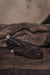 Dark brown leather belt with silver buckle on a textured brown surface