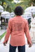 Person wearing a pink shirt with a black design outdoors