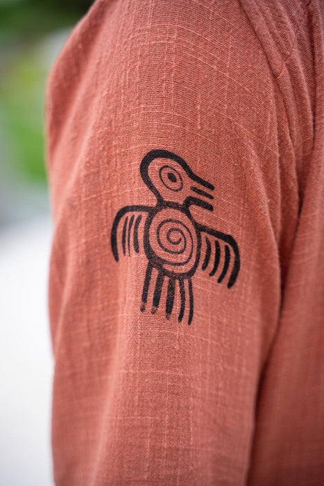Brown fabric with a black bird-like symbol on a blurred natural background