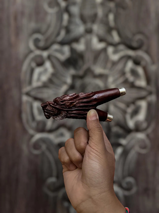 Hand holding a decorative wooden object against an ornate wooden background
