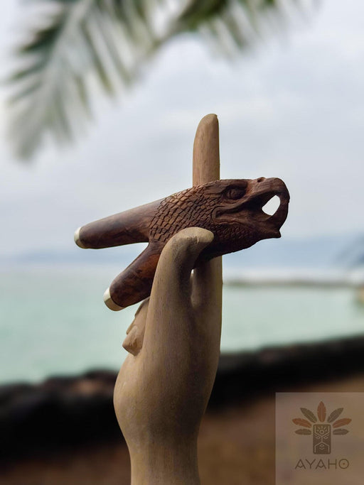 Wooden handcrafted tool held by a hand with a blurred natural background