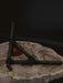 Wooden triangle with a string and small round object on a textured surface