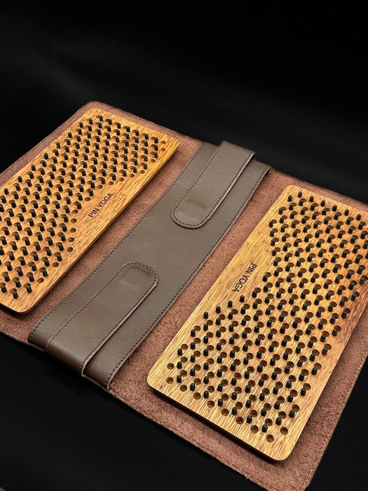 Two wooden massage boards with a brown leather case on a black background