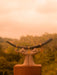 Statue of hands holding a large bull's horn with a blurred natural background