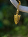 Gold pendant shaped like a traditional weapon on a blurred natural background