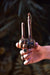 Hand holding a wooden tool with decorative elements against a dark background
