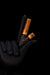 Two makeup brushes with wooden handles held by a dark-skinned hand against a black background