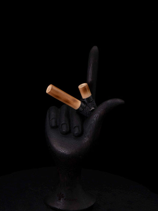 Black hand holding two cigarettes with smoke on a black background