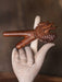 Wooden dragon figurine on a stone hand against a brown background