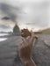 Hand holding a shell with a blurred beach background