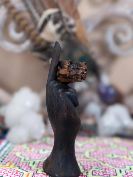 Wooden sculpture of a hand holding a small object against a blurred background