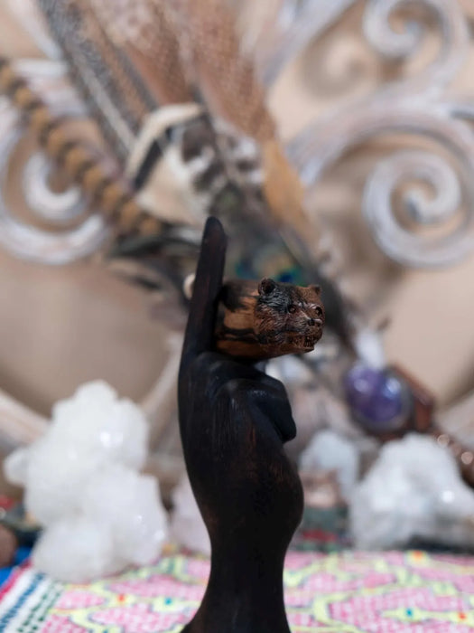 Black hand holding a piece of wood against a blurred background with crystals and patterns