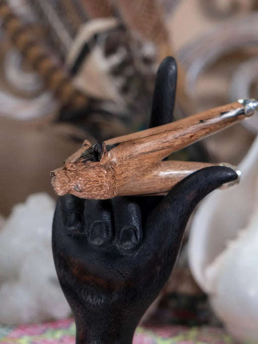 Black cast iron hand holding a wooden object with a decorative background