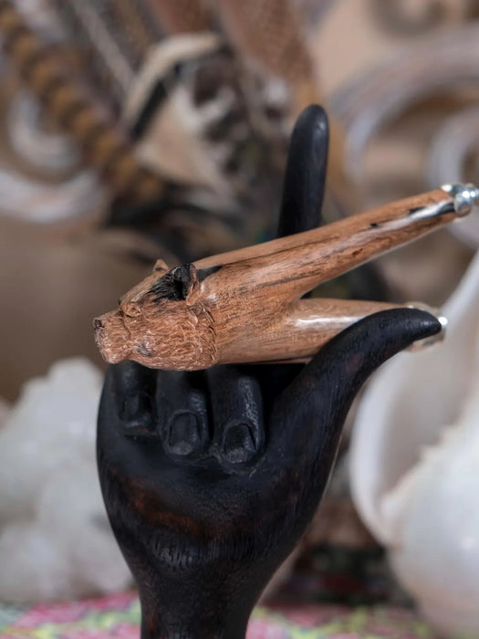 Black cast iron hand holding a wooden object with a decorative background