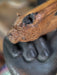 Close-up of a wooden object with a bear head design held by a person wearing black gloves.