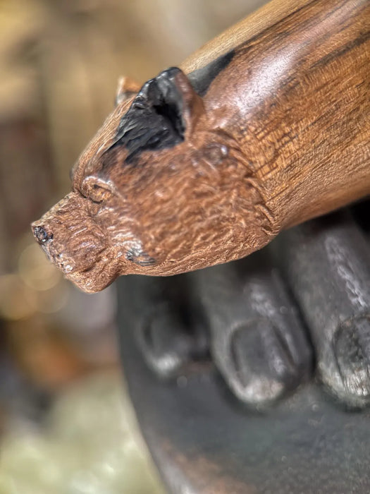 Wooden handle with a carved animal head design, held by a black gloved hand.