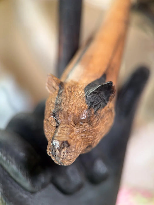 Close-up of a wooden tool handle with a blackened tip, held by a gloved hand.