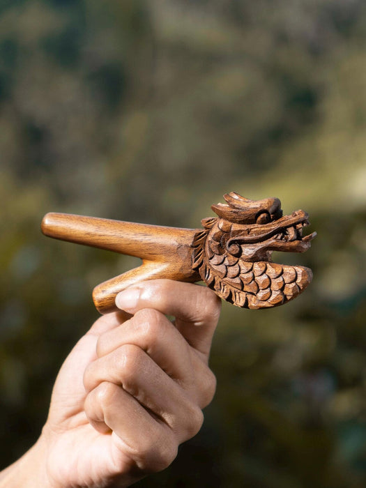 Wooden dragon handle held by a hand with a blurred natural background
