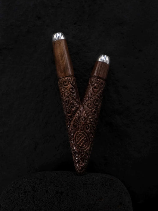 Two wooden pens with silver accents on a dark textured background