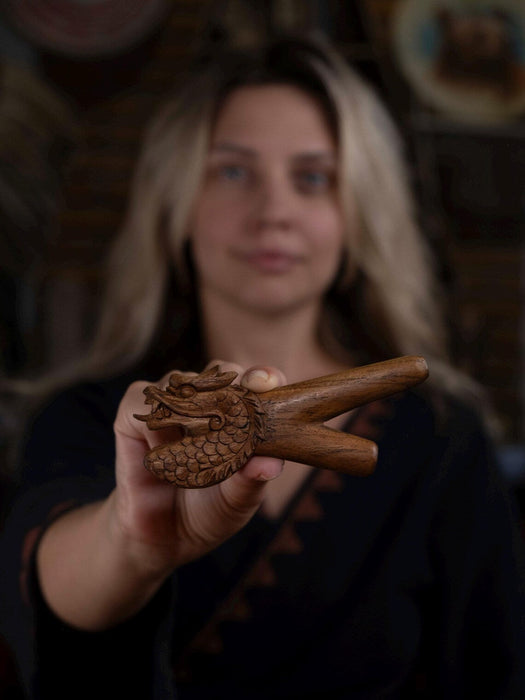 Person holding a wooden dragon figurine with a blurred background