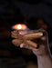 Hand holding a wooden incense burner with a blurred candle in the background