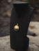 Gold necklace on a black mannequin bust with a blurred natural background
