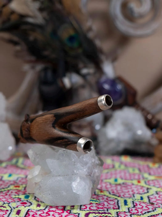 Wooden smoking pipe with silver accents on a crystal base with a colorful fabric background
