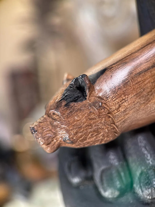 Wooden handle with a carved bear head detail on a blurred background