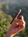 Hand holding a decorative object against a blurred natural background