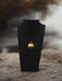 Gold necklace on a black stand with a blurred natural background