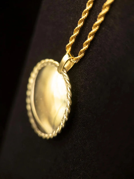 Gold necklace with a round pendant on a black background
