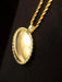Gold necklace with a round pendant on a black background