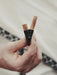 Hand holding two lip liners against a blurred background