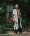 A man stands in a forest, his demeanor calm and grounded, wearing a Boho tribal cotton poncho, embodying a unisex, earthy shamanic style.