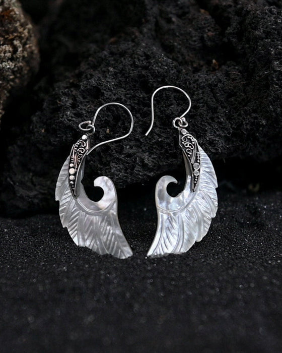 Exquisite Angel Wings earrings, crafted from lustrous mother-of-pearl and detailed sterling silver, radiating aesthetic grace and ethereal charm