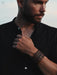 Rust-brown buffalo leather bracelet, hand-shaped and naturally dyed, with a triple-infinity loop design for grounding energy.