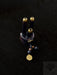 Decorative item with three cylindrical elements and a pendant on a dark background