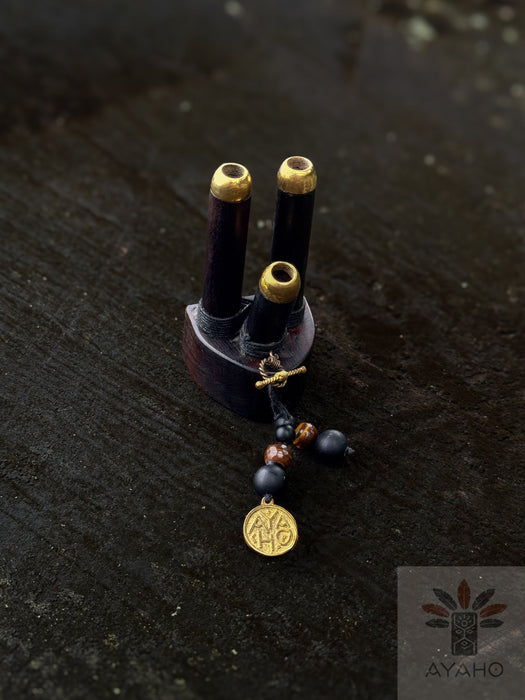 Small wooden object with gold accents and beads on a dark surface, featuring the AYAOH brand.