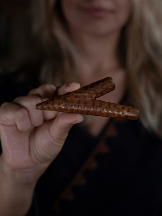 Hand holding a wooden object against a blurred background