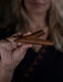 Hand holding a wooden object against a blurred background